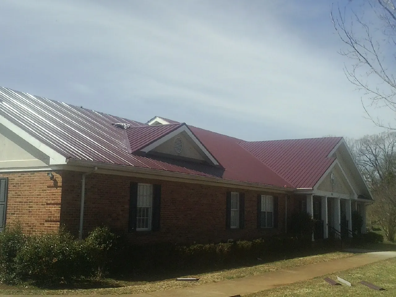 Red metal roof with gabled entries on a long brick building in Sardis